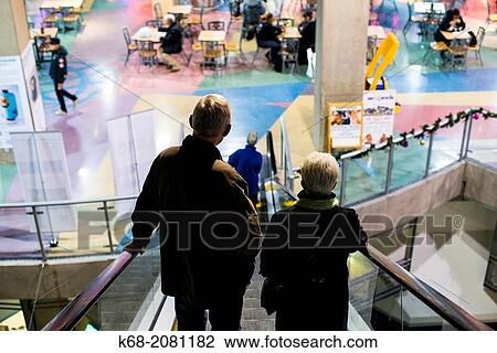 A middle-aged couple goes down an escalator at International Village mall in downtown Vancouver, BC, Canada. View Large Photo Image Stock Image - A middle-aged couple goes down an escalator at International Village mall in downtown Vancouver, BC, Canada.. Fotosearch