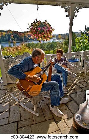 A middle-aged guitarist plays for his wife's enjoyment on the front porch of a country house in Michigan Note autumn colors View Large Photo Image Stock Image - A middle-aged guitarist plays for his wife's enjoyment on the front porch of a country house in Michigan Note autumn colors. Fotosearch