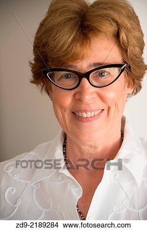 Picture - A middle aged woman smiles through her cat's-eye glasses.. Fotosearch