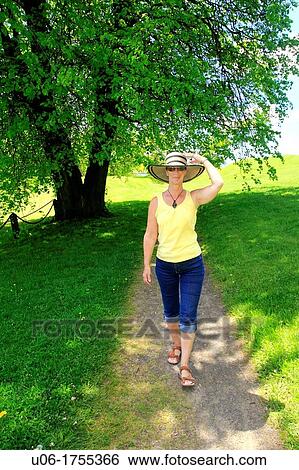 a middle aged woman walking along a path through trees in a field during spring View Large Photo Image Stock Photograph - a middle aged woman walking along a path through trees in a field during spring. Fotosearch