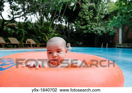 A mixed ethnicity child floats in an orange inner tube in a swimming pool View Large Photo Image Stock Image - A mixed ethnicity child floats in an orange inner tube in a swimming pool. Fotosearch