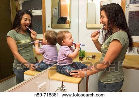 A mother and her baby daughter in their bathroom at home, both brushing their teeth View Large Photo Image Stock Image - A mother and her baby daughter in their bathroom at home, both brushing their teeth. Fotosearch