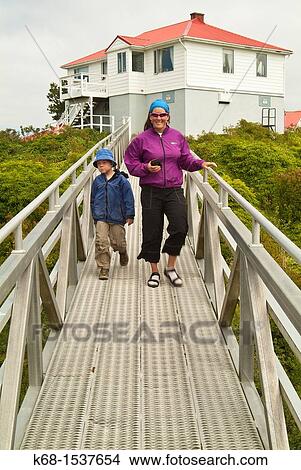 Picture - a mother and her son on the bridge leading to the lighthouse at Friendly Cove, BC, Canada. Fotosearch