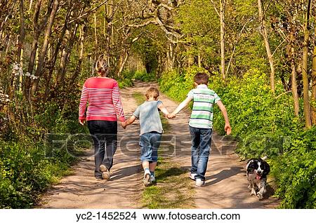 A mother and her two sons walk the dog down a country track in Spring in the Uk View Large Photo Image Picture - A mother and her two sons walk the dog down a country track in Spring in the Uk. Fotosearch
