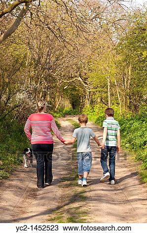 A mother and her two sons walk the dog down a country track in Spring in the Uk View Large Photo Image Stock Image - A mother and her two sons walk the dog down a country track in Spring in the Uk. Fotosearch
