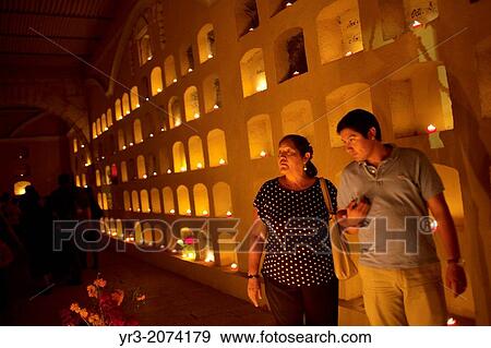 Stock Photo - A mother and his son visit the San Miguel cemetery during the Day of the Dead celebrations in Oaxaca, Mexico. The Day of the Dead celebration is a tradition that honors the deceased.. Fotosearch