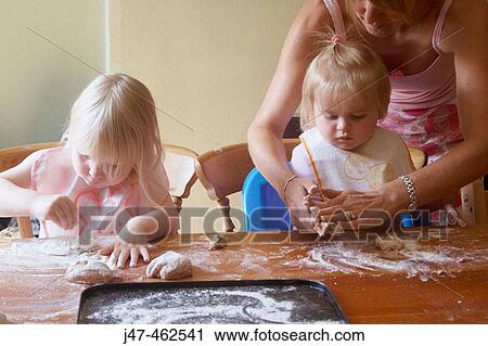 Stock Image - A mother baking with 2 young girls. Fotosearch