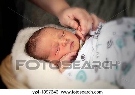 Stock Image - A mother holding the hand of her newborn baby boy. Fotosearch
