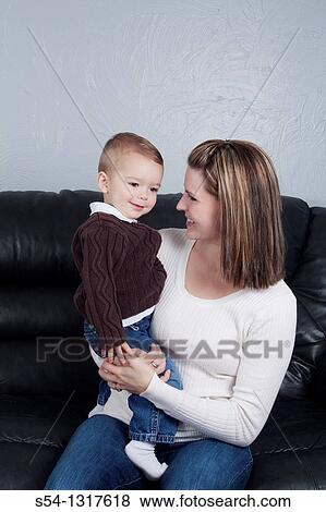 A mother holds her young son indoors. View Large Photo Image Stock Photo - A mother holds her young son indoors.. Fotosearch