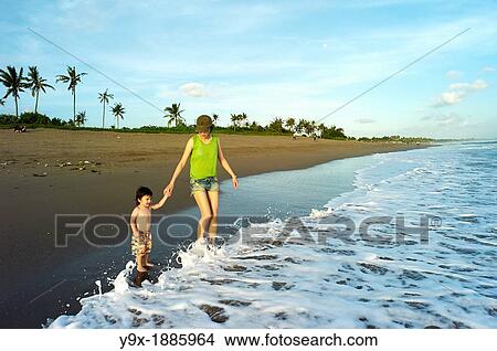 A mother taking her young son by the hand on the beaches of Bali View Large Photo Image Picture - A mother taking her young son by the hand on the beaches of Bali. Fotosearch