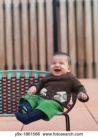 A multi ethnic baby boy with a funny knit sweat sits on a chair View Large Photo Image Stock Photograph - A multi ethnic baby boy with a funny knit sweat sits on a chair. Fotosearch