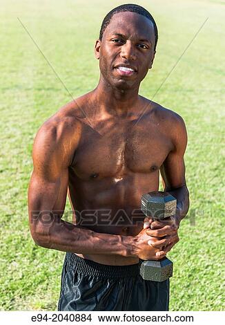 A muscular shirtless 24 year old black man holding a dumbbell outdoors. View Large Photo Image Picture - A muscular shirtless 24 year old black man holding a dumbbell outdoors.. Fotosearch