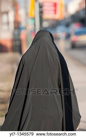 Stock Photo - A Muslim woman wearing a Burka walks Downtoney Stanton Rd in Coventry, West Midlands, England. Fotosearch