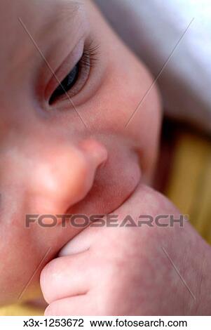A new born baby with a hand in mouth View Large Photo Image Stock Image - A new born baby with a hand in mouth. Fotosearch