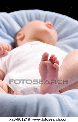 A newborn baby dressed in a white bodysuit lies on a blue blanket The angle is from his feet View Large Photo Image Stock Photo - A newborn baby dressed in a white bodysuit lies on a blue blanket The angle is from his feet. Fotosearch