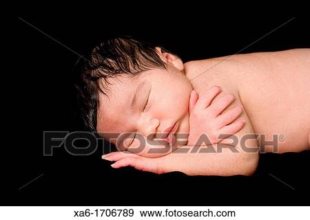 Stock Photo - A newborn baby lies sleeping Lots of hair Close up. Fotosearch