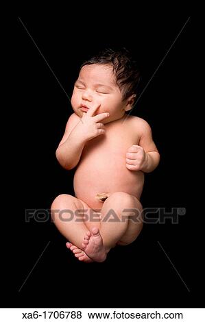 A newborn baby lies sleeping on a black backdrop Close up View Large Photo Image Stock Photo - A newborn baby lies sleeping on a black backdrop Close up. Fotosearch