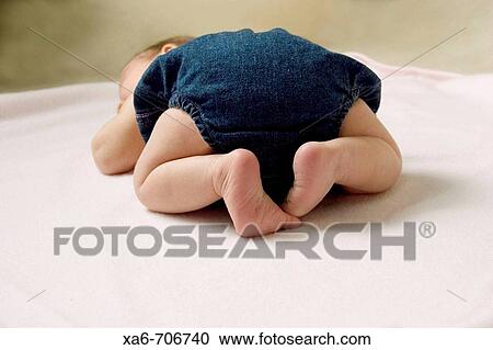 A newborn baby wearing a denim diaper cover lies sleeping on her front on a pink blanket. View Large Photo Image Stock Image - A newborn baby wearing a denim diaper cover lies sleeping on her front on a pink blanket.. Fotosearch