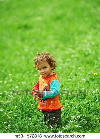 Stock Photo - A one year old baby girl playing in a green meadow. Fotosearch