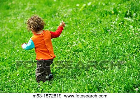 A one year old baby girl playing in a green meadow View Large Photo Image Stock Photo - A one year old baby girl playing in a green meadow. Fotosearch