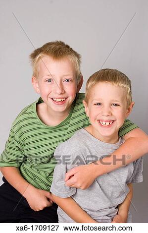 Stock Photo - A pair of young blond haired boys, brothers, against a grey background. Fotosearch