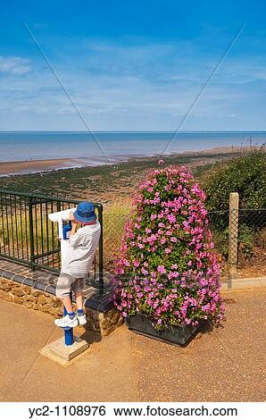 Stock Photograph - A pay to view telescope looking out to sea being used by a young child at Hunstanton, North Norfolk, Uk. Fotosearch