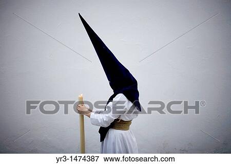 Stock Photo - A penitent holds a candle during an Easter Holy Week procession in Carmona village, Seville province, Andalusia, Spain, April 19, 2011. Fotosearch