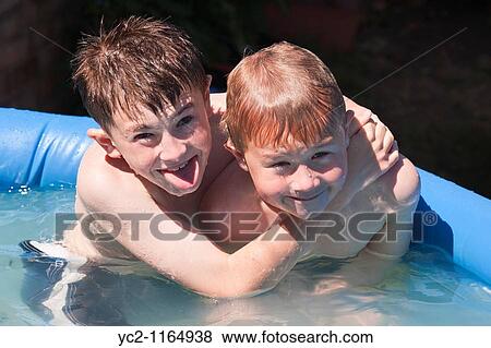 Stock Photo - A photo of two boys 6 & 10 in a small garden swimming pool in the Uk. Fotosearch