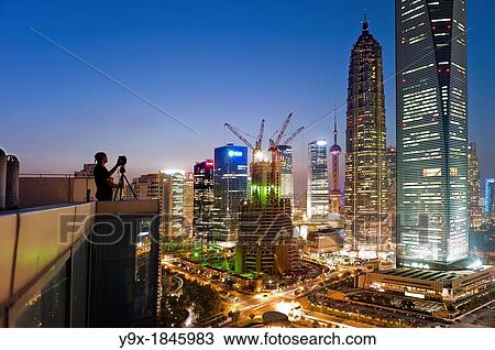 A photographer sets up his shot of Jin Mao Tower, the Shanghai World Financial Center and a building under construction View Large Photo Image Stock Image - A photographer sets up his shot of Jin Mao Tower, the Shanghai World Financial Center and a building under construction. Fotosearch