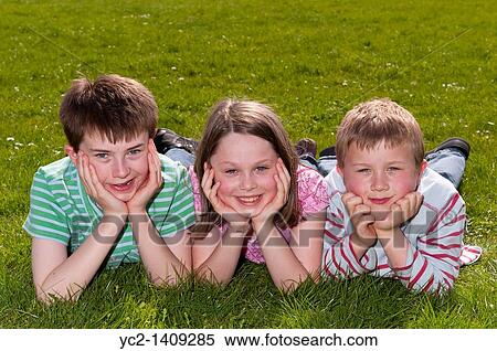 A picture of a girl and two boys outdoors laying on the grass in the Uk View Large Photo Image Stock Photography - A picture of a girl and two boys outdoors laying on the grass in the Uk. Fotosearch