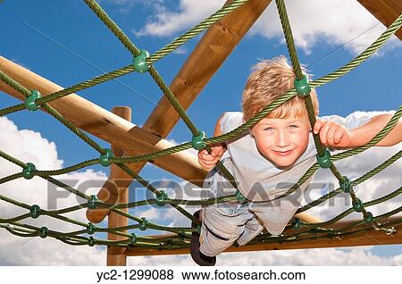 Stock Photo - A picture of a seven year old boy on a climbing frame in the Uk. Fotosearch