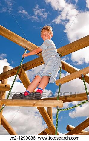 Stock Photograph - A picture of a seven year old boy on a climbing frame in the Uk. Fotosearch