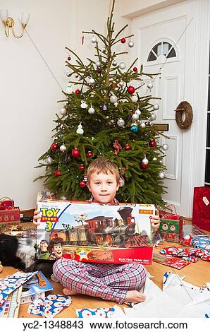 A picture of a seven year old boy opening christmas presents under the tree in the Uk View Large Photo Image Stock Image - A picture of a seven year old boy opening christmas presents under the tree in the Uk. Fotosearch
