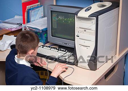 Stock Photo - A picture of a ten year old boy on his computer in his bedroom in the Uk. Fotosearch