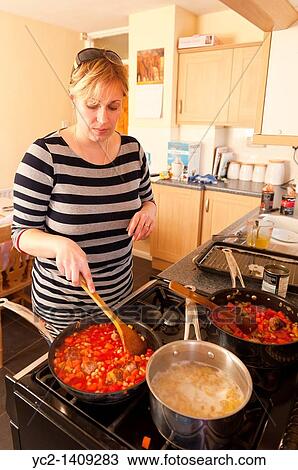 A picture of a woman in her thirties cooking a pasta dish at home in the kitchen View Large Photo Image Stock Image - A picture of a woman in her thirties cooking a pasta dish at home in the kitchen. Fotosearch