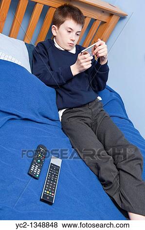 A picture of an eleven year old boy playing with his ipod touch in his bedroom in the Uk View Large Photo Image Stock Photo - A picture of an eleven year old boy playing with his ipod touch in his bedroom in the Uk. Fotosearch