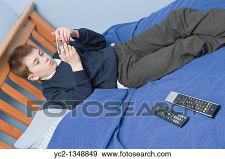 A picture of an eleven year old boy playing with his ipod touch in his bedroom in the Uk View Large Photo Image Stock Photo - A picture of an eleven year old boy playing with his ipod touch in his bedroom in the Uk. Fotosearch
