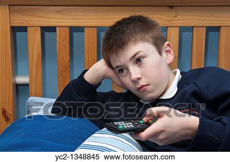 Stock Photography - A picture of an eleven year old boy watching TV in his bedroom in the Uk. Fotosearch