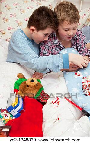 A picture of two boys 11 and 7 opening christmas presents in bed from their stockings in the Uk View Large Photo Image Stock Photo - A picture of two boys 11 and 7 opening christmas presents in bed from their stockings in the Uk. Fotosearch