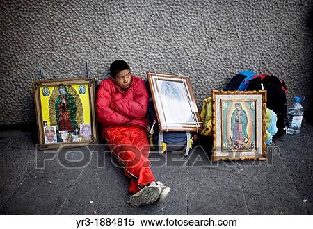 Stock Photography - A pilgrim sits by images of Our Lady of Guadalupe virgin in Mexico City, December 6, 2008. Fotosearch
