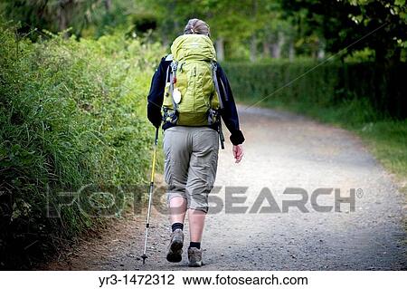 Stock Image - A pilgrim walks in the shade in a track of the French Way that leads to Santiago de Compostela, Way of Saint James, Galicia region, Spain. Fotosearch