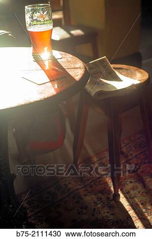 A pint of a beer in a Pub on top of a table with one newspaper on a stool and the sunlight streaming through a window. Yorkshire Dales, England, UK, Europe. View Large Photo Image Stock Image - A pint of a beer in a Pub on top of a table with one newspaper on a stool and the sunlight streaming through a window. Yorkshire Dales, England, UK, Europe.. Fotosearch