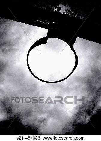 A playground basketball hoop is captured in sillouette against a dramatic sky. View Large Photo Image Stock Photograph - A playground basketball hoop is captured in sillouette against a dramatic sky.. Fotosearch