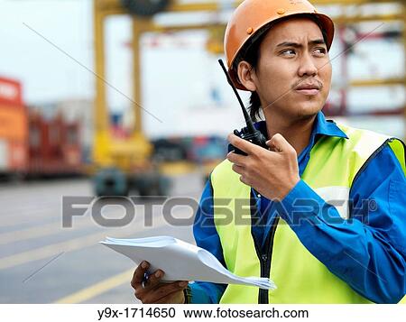 A port worker talking over and radio overseeing work at a commerical container and Palm Oil port in Johor, Malaysia View Large Photo Image Stock Image - A port worker talking over and radio overseeing work at a commerical container and Palm Oil port in Johor, Malaysia. Fotosearch