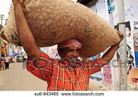 Stock Photography - A porter carrying a large bag of shallots on his head Kollam, Kerala, India. Fotosearch