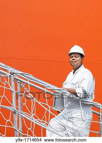 A portrait of a inspector at a commerical container and Palm Oil port in Johor, Malaysia walking up a stairway to the deck of a ship View Large Photo Image Picture - A portrait of a inspector at a commerical container and Palm Oil port in Johor, Malaysia walking up a stairway to the deck of a ship. Fotosearch