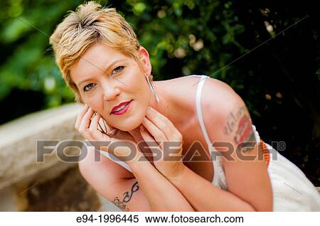 A portrait of a smiling 44 year old blond woman wearing a white summer dress in a garden setting. View Large Photo Image Stock Photography - A portrait of a smiling 44 year old blond woman wearing a white summer dress in a garden setting.. Fotosearch