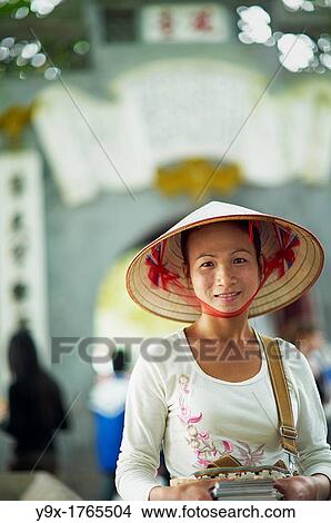 A portrait of a Vietnamese woman wearing a n? n lB or a traditional Vietnamese straw hat contrasted with modern clothes View Large Photo Image Picture - A portrait of a Vietnamese woman wearing a n? n lB or a traditional Vietnamese straw hat contrasted with modern clothes. Fotosearch