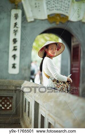 A portrait of a Vietnamese woman wearing a n? n lB or a traditional Vietnamese straw hat contrasted with modern clothes View Large Photo Image Stock Image - A portrait of a Vietnamese woman wearing a n? n lB or a traditional Vietnamese straw hat contrasted with modern clothes. Fotosearch