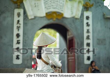 A portrait of a Vietnamese woman wearing a n? n lB or a traditional Vietnamese straw hat contrasted with modern clothes View Large Photo Image Stock Image - A portrait of a Vietnamese woman wearing a n? n lB or a traditional Vietnamese straw hat contrasted with modern clothes. Fotosearch